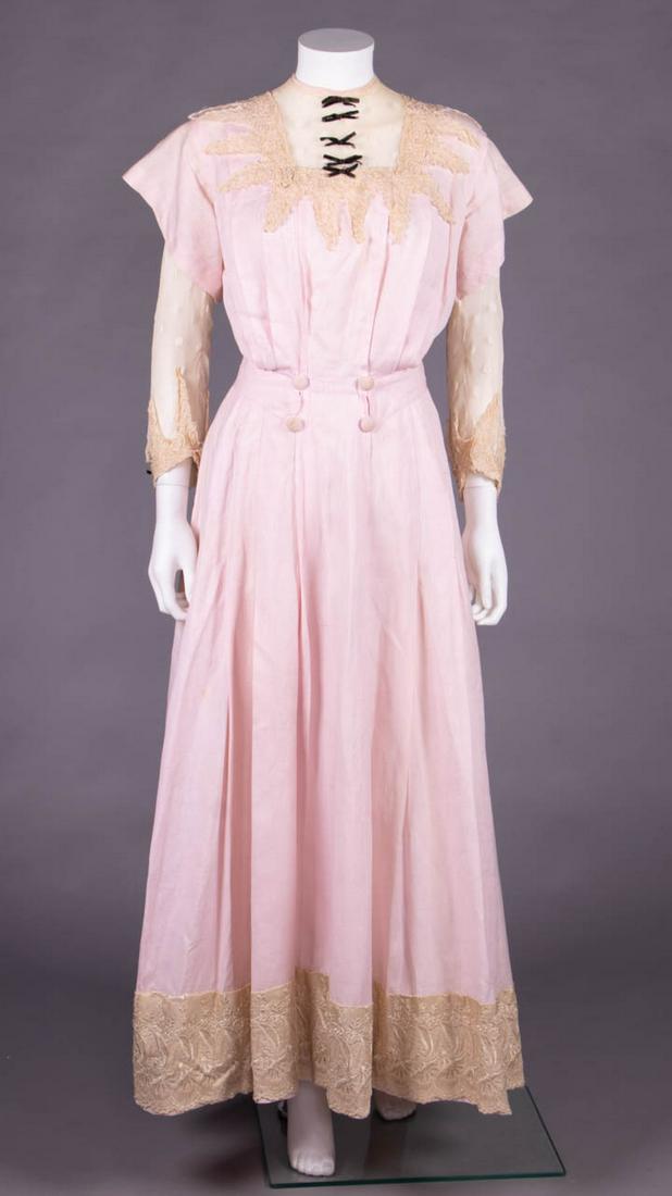 PINK LINEN DAY DRESS, 1910-1912: Pink linen dress w/ inserted neck yoke & undersleeve w/ polka dot, mm lace appliqué, corded embroidered & black silk velvet bows, broad applied front hem band of fine Heilmann embroidery on silk,