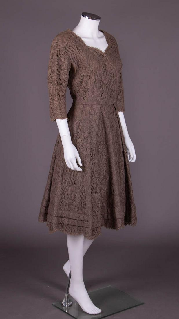 YSL DESIGNED & CHRISTIAN DIOR LABELED ADAPTATION, 1960: Taupe guipure lace dress lined in cotton, scalloped neckline & cross draped bodice, 3/4 length sleeves, box pleated skirt w/ double tuck about scalloped hem, label "Christian Dior Exclusive Adaptation