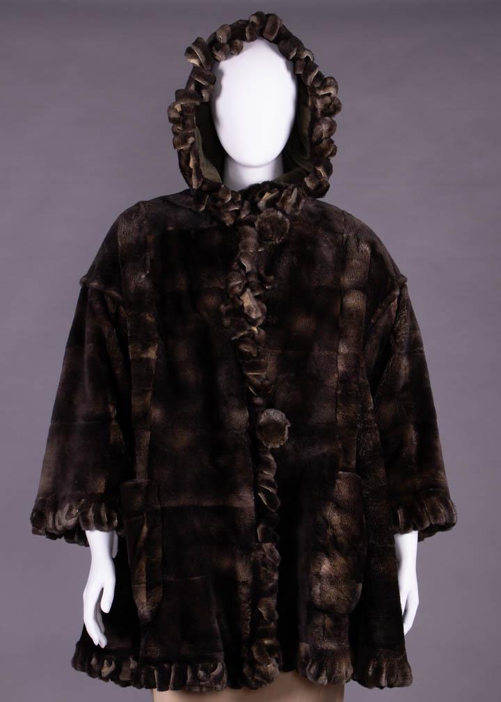 FENDI REVERSIBLE FUR & CASHMERE COAT, ITALY, c. 1983: Reversible cropped hooded fur coat in khaki green cashmere reversing to gray/brown sheared pieced muskrat w/ fur cut fringe loops on all edges, patch pockets, wide cut drop SH, large self button & loo