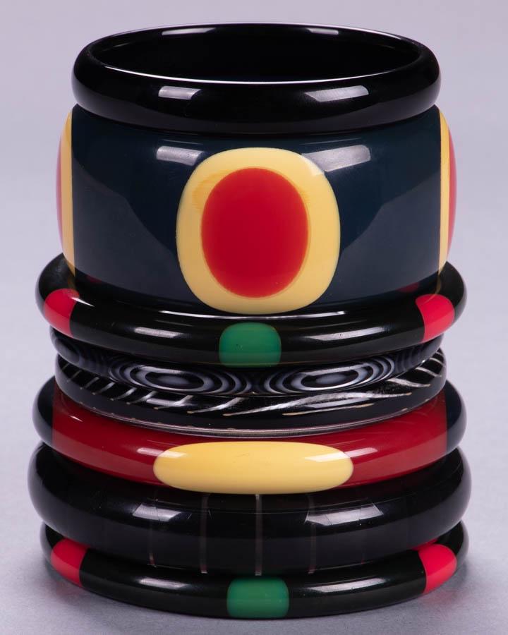 FOUR SHULTZ & J. EVANS BANGLES, AMERICA, MODERN: 4 bangles signed "Shultz": 1 wide navy blue w/ layered cherry red & yellow oval, 2 identical black w/ alternating green & red spot motif, 1 red w/ alternating yellow & black lozenge motif; 1 wide clea