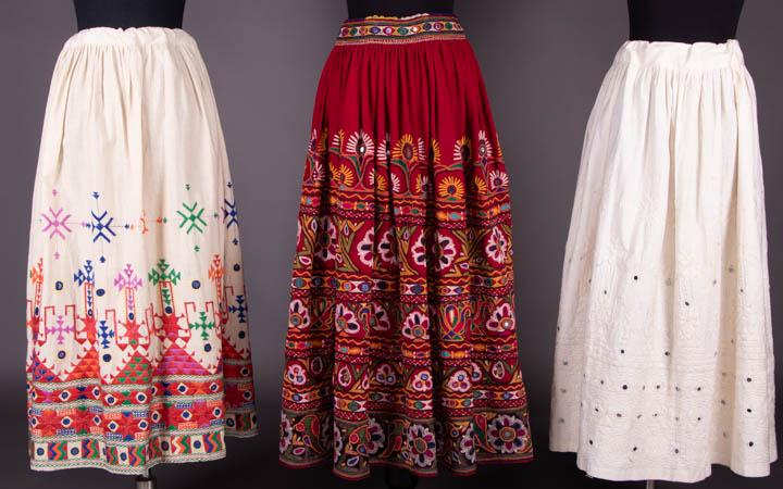 THREE EMBROIDERED SKIRTS, INDIA, MID 20TH C: 1 white cotton embroidery on white cotton skirt w/ mirror work, W up to 33", L 32", (tiny-1.5" stains, 0.75" seam opening W band); 1 red cotton w/ cotton embroidery & mirror work, label "Made in India