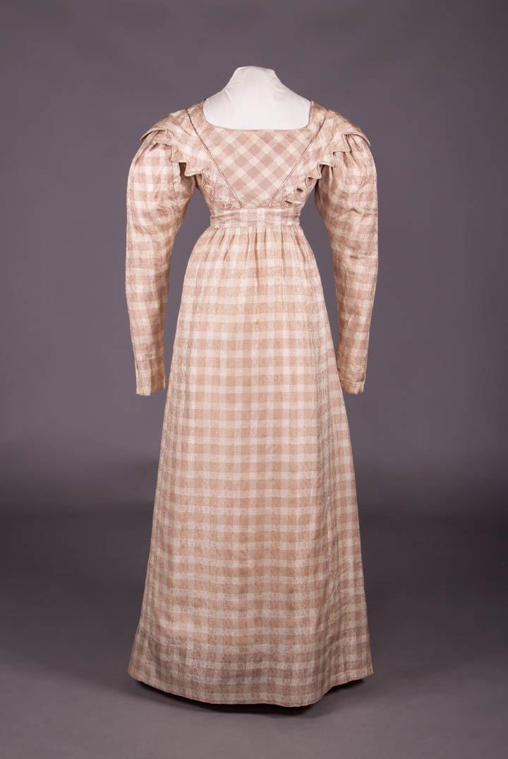 SILK DAY DRESS, LATE 1820s: Mauve & cream patterned gingham check silk day dress w/ bias cut bodice front panel w/ applied graduated Van Dyke edged panels from front W extending over SHs to either side of CB W trimmed w/ twisted