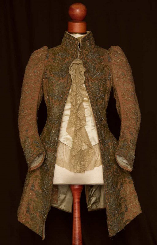 LADIES BEADED JACKET, 1888-1892: Dusty rose in style of men's 18th C. court jacket, embroidered all over w/ metallic gold thread & cut steel beads, heavier metallic embroidered floral & tassle design on front, cuffs, stand collar, fa