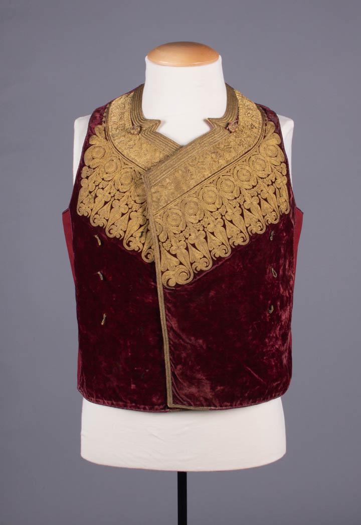 COURT EMBROIDERED VEST, GREECE, LATE 19TH: Silk velvet w/ metallic embroidery, galloon & soutache, lined in white cotton, CH 41", L 21", (bead loss on buttons, wear, crushing to velvet, tarnish, tiny-0.25" holes, 3" line of black stains at bac