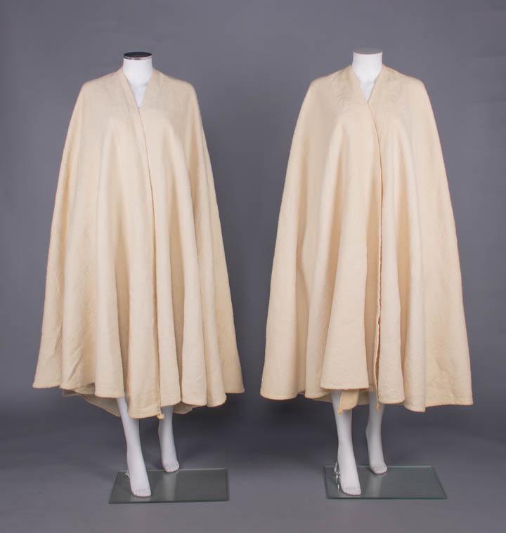 TWO CREAM WOOL BURNOOSE, MOROCCO OR TUNISIA, c. 1937: Both fulled wool w/ twined braid & appliquÃ© embroidered top seam on â€œhood” & knotted netting inserted godet between openings: 1 w/ cream embroidery on hood, SH-SH 18", L 48"-56", (pilli