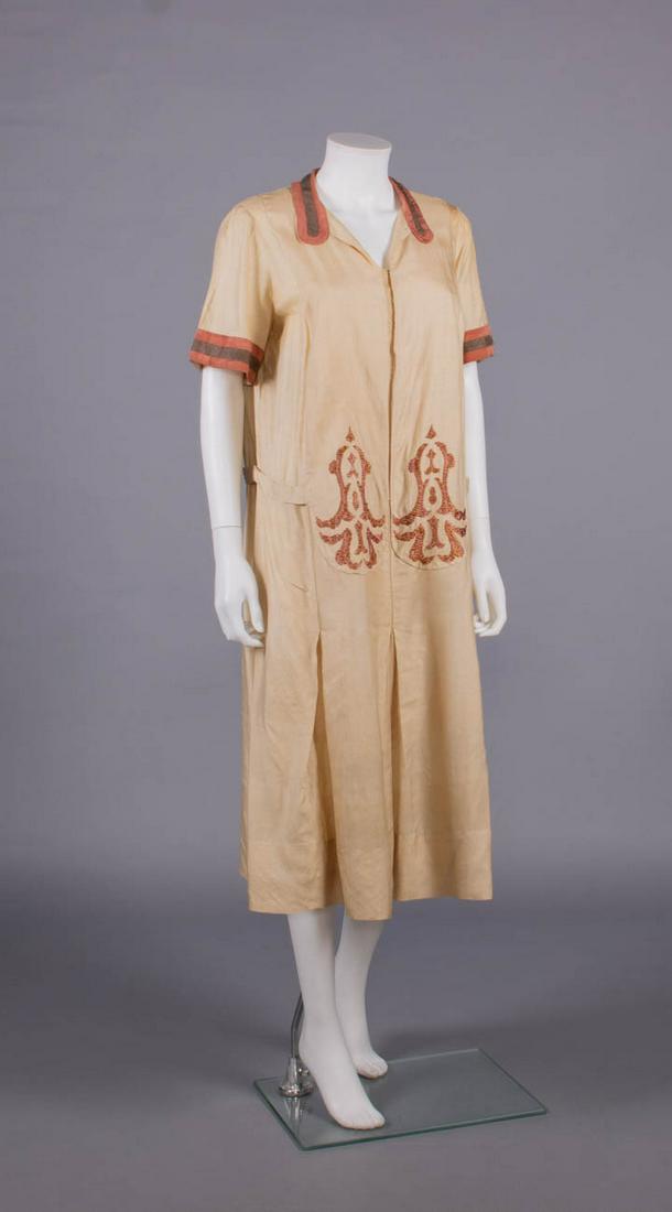 EMBROIDERED SILK PONGEE DAY DRESS, c. 1923: Silk pongee day dress w/ inset front panels extending over skirt front w/ Islamic inspired multi-colored silk floss embroidered motifs, cinnamon silk lobed collar & short sleeve cuffs w/ applied chest