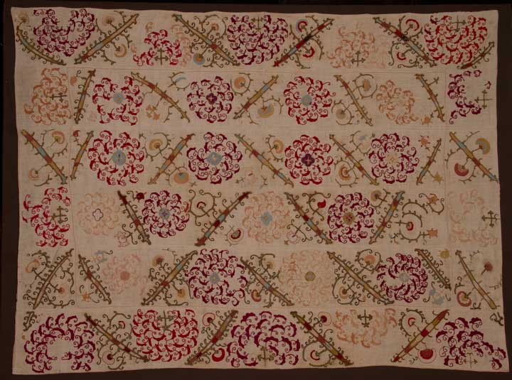 EMBROIDERED SUZANI, CENTRAL ASIA, c. 1900: Embroidery on natural cotton ground, stylized blossoms & batons in red, yellow, peach, light blue & black, large scale floral print backing, 68" x 91", (moderate fading & scattered ground repairs) ver