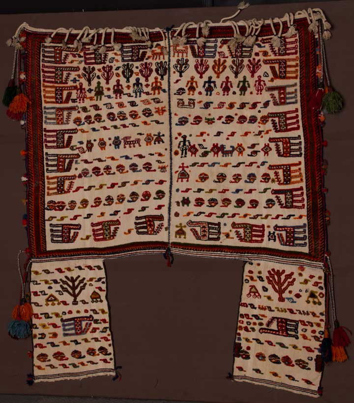 PACK ANIMAL BLANKET, S. AMERICA, 1930-1940: Flat weave cream wool center & side flaps, woven high pile men, women, llamas, trees & symbols in various colorful combinations, long braided & tasseled wool fringe, 46" x 45", attached side flaps, 14