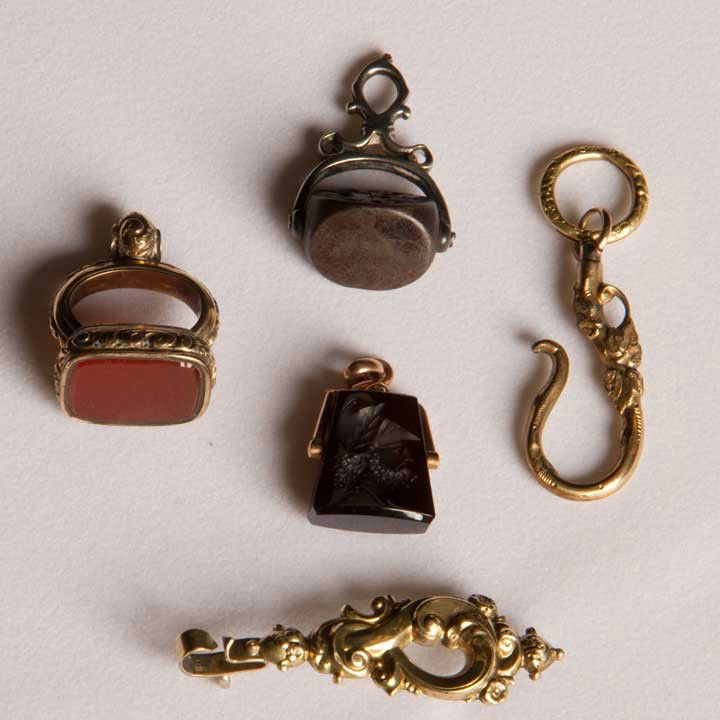FOUR WATCH FOBS, 19TH C: 1 14K gold & intaglio jet portrait, 4.0 dwt; 1 18K gold & carnellian, 6.8 dwt; 1 GP gold hook; 1 silver w/ heraldic stamp, 11.3 dwt; t/w 1 14K gold pendant pin, (missing pendant) very good-excellent.