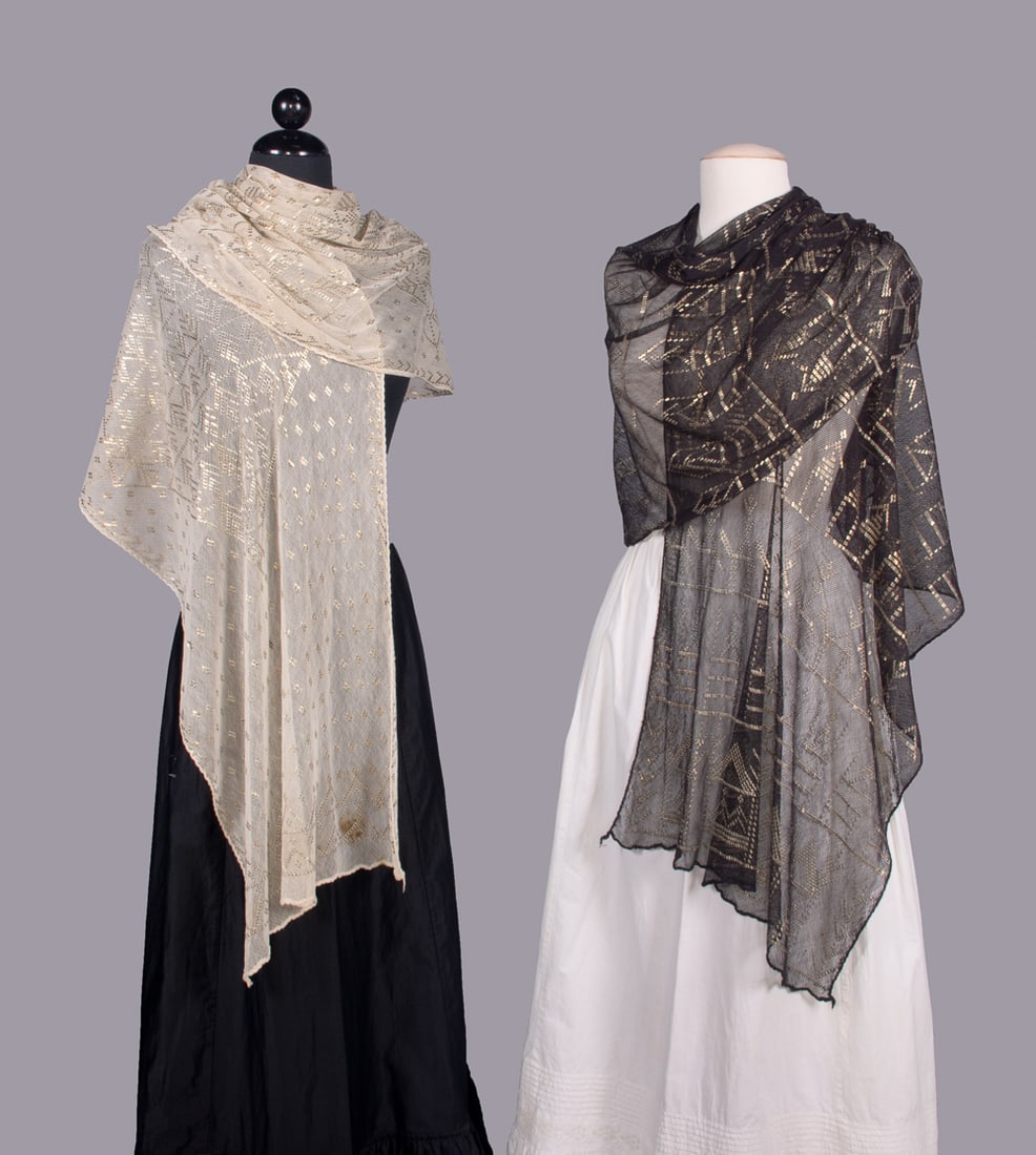 TWO ASSUIT SHAWLS, EGYPT, 1920s: 1 white assuit w/ silver tone metallic in mirrored symmetrical diamond motif & palmettes, 18” x 102”, (light stains up to 2”, minor tarnish, light wear to edges); 1 black assuit shaw