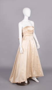 COUTURE SILK EVENING GOWN, 1950s: Sleeveless champagne peau de soie evening gown w/ flat neckline, fitted W w/ horizontal knife pleats, folded flat panel pleated to back neckline & W with cascading tails, slightly trained skirt, lined