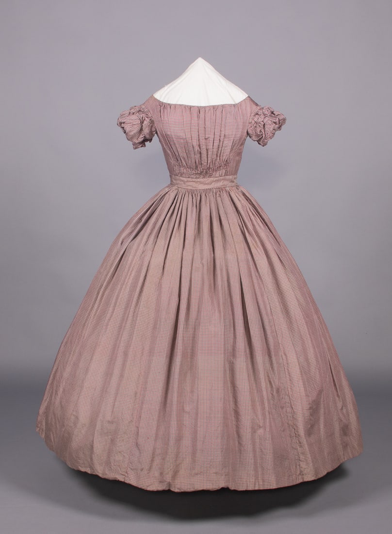 SILK TATTERSALL CHECK AFTERNOON DRESS, c. 1850: Purple, red & blue tattersall check silk young lady’s dress w/ piped wide bateau neckline, armscye, double puff short sleeve & fitted waistband, fullness over B ruched above CF & CB W, finely cartri