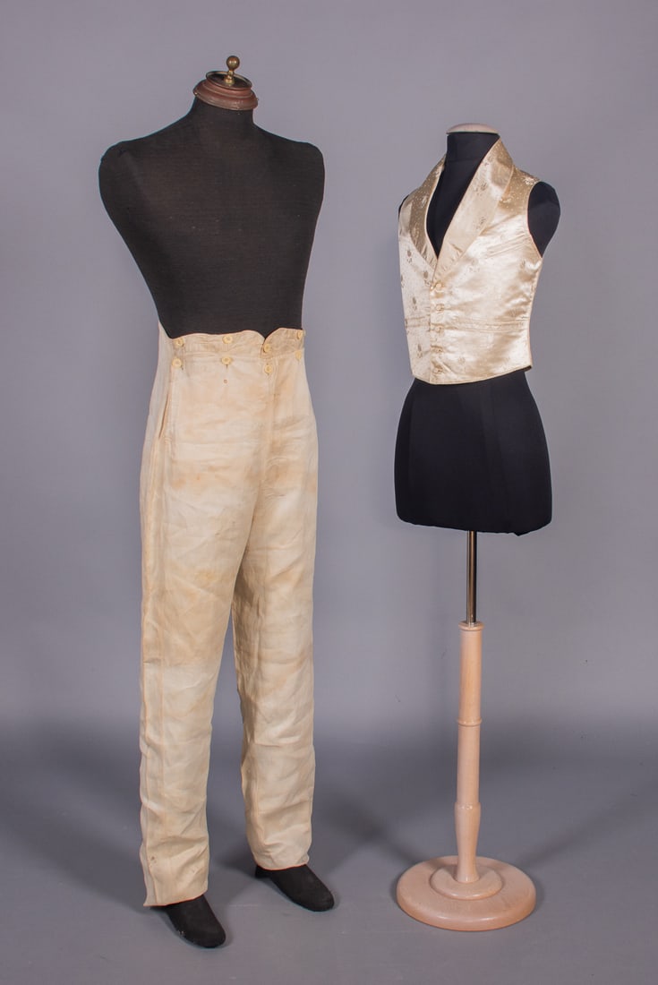 WEDDING WAISTCOAT & TROUSERS, 1840s: 1 wedding waistcoat of white silk damask, back of plain white linen w/ self-covered buttons, lacing at CB, back & lining of cream linen, March 23, 1841, CH 34”, L 17”, (few small stains, f