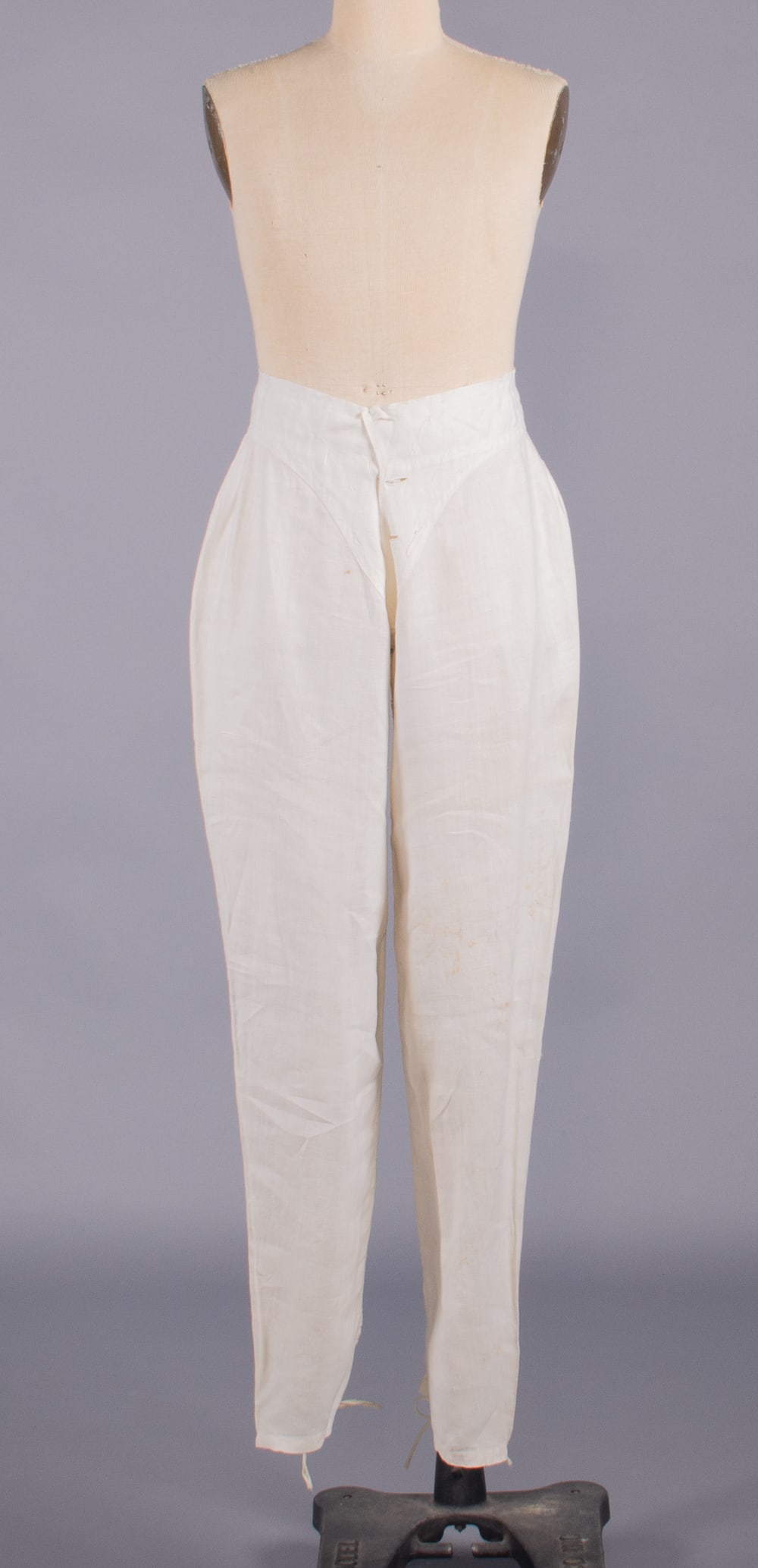 GENTS WHITE LINEN DRAWERS, 1850s: White linen drawers w/ buckle closure at back, buckle stamped “1854”, W 26”, inseam 30”, (light discoloration, small light stains, missing all buttons, pulls, minor tarnish to buck