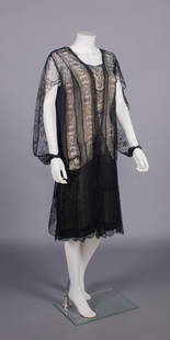 GABRIELLE CHANEL CHANTILLY LACE EVENING DRESS, MID 1920s: Evening dress constructed from 1860s Chantilly lace shawl w/ black silk crepe de chine insertions & underskirt, slashed long sleeve w/ fitted snap closure cuff, label “Chanel”, couture tape fa