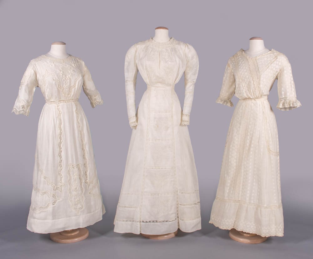 THREE COTTON OR LINEN LINGERIE DRESSES, 1910-1912: 1 white cotton mull w/ Shiffili embroidery in border & mirror image floral sprig motif, asymmetrical F & B c. 1912, B 34”, W 26”, L 55”, (light discoloration at SH, few breaks in lac