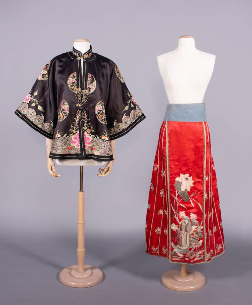 EMBROIDERED COAT & PAIRED MANDARIN SKIRT, CHINA, 1920-1940s: 1 black silk satin coat embroidered w/ silk satin stitch, CH 40”, L 27”, (few loose stitches at closures, trim loose CB collar, few minor pulls in embroidery, lining discolored); 1 scarlet