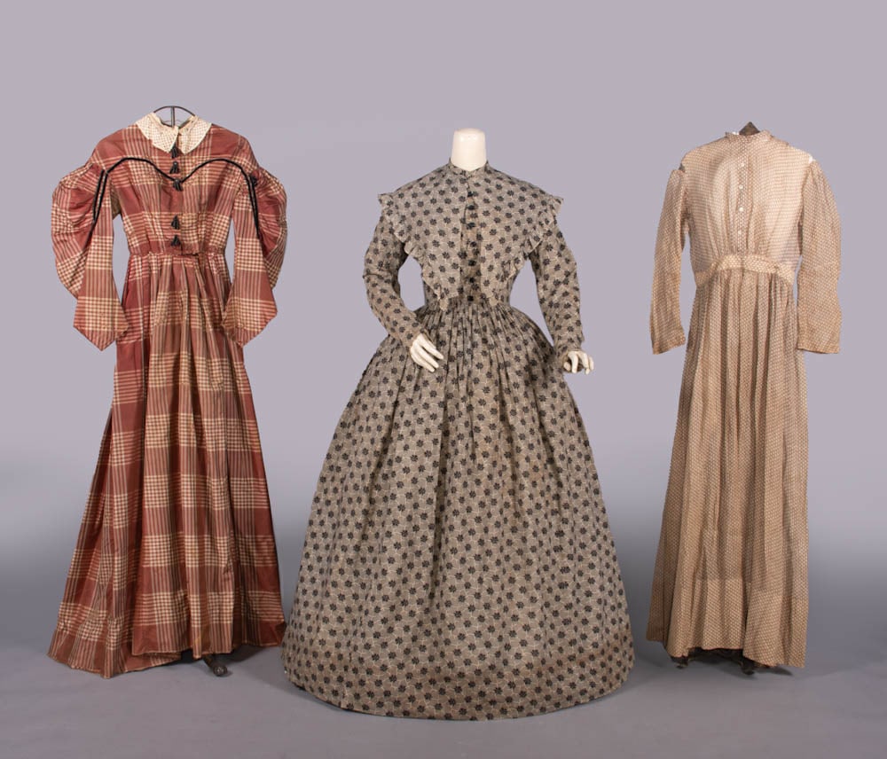 PRINTED COTTON DAY DRESS & PELERINE, 1850s: Entirely hand stitched printed cotton day dress w/ band collar, black cast CF button closures, 2-pc fitted sleeve w/ reinforcement at elbow, full cartridge pleated skirt & matching pelerine w/ self-ru