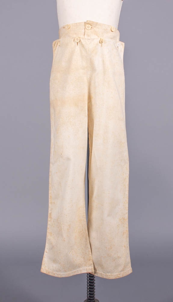 YOUNG MANS FALL FRONT COTTON TROUSERS, 1820-1840: Cotton twill flared trousers w/ fall front, bone self-covered buttons, W 22”, inseam 21”, (broad foxing spots/light discoloration throughout, light staining up to 3” at seat, 0.25&rd