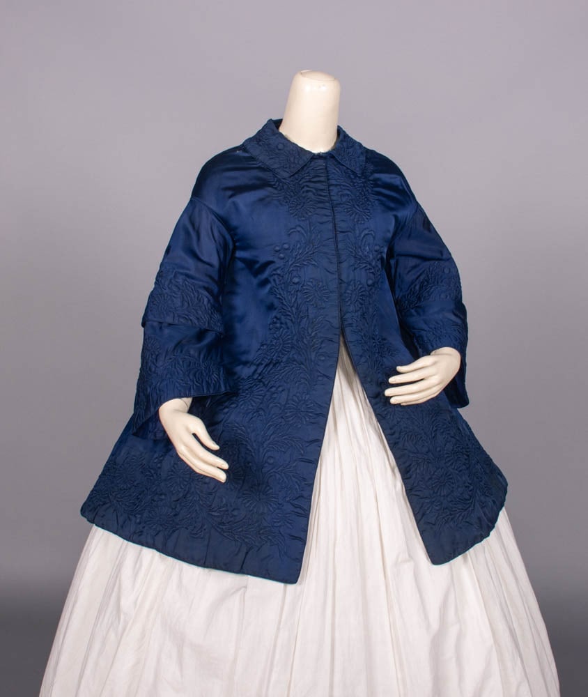 TAMBOUR QUILTED SILK PALETOT, c. 1844: Sapphire silk satin tambour hand quilted w/ shirt collar, faux cape panel at CB, tiered bell sleeve & CF hook & eye closures above B, piping throughout, diamond quilted china silk lining, c. 1844, B 4