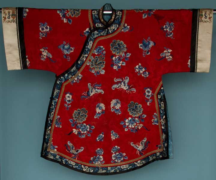 EMBROIDERED RED ROBE, CHINA, 19TH C: Crimson silk damask, Peking knot, gold couching & satin stitch embroidery of flowers & butterflies in shades of blue, black silk embroidered borders in blue fllowers, white silk sleeve bands motifs al