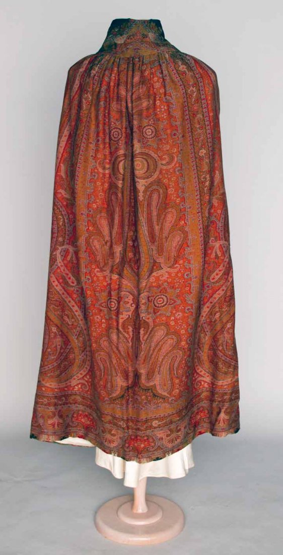 WOVEN WOOL PAISLEY CAPE, 1900-1920: Fashioned from 19th C paisley shawl, boteh patterns in maroon, rust, red & brown, 2 front openings for hands, self fabric tie at neck, excellent.