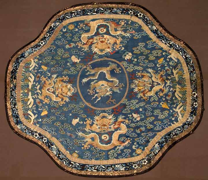 ROUND KOSSU TABLE COVER, 19TH C: Silk tapestry weave, blue ground w/ motifs of large dragons, birds, shells, bats & clouds, blue floral embroidered border, 41.5" x 46.5", (some areas w/ significant silk losses, stains & mends) poor-f