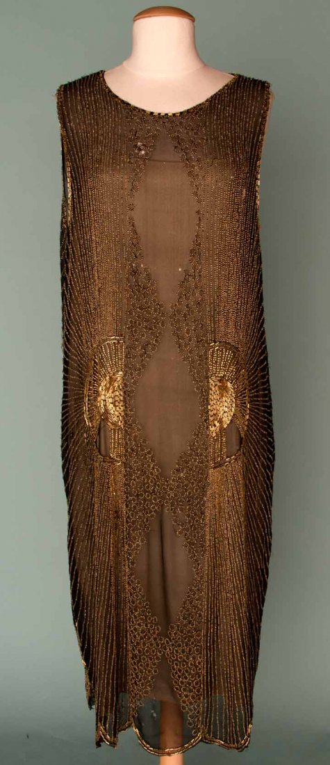 GOLD BEADED PARTY DRESS, MID 1920s: Black silk chiffon, gold bead design in radiating center sun, small rings around voided diamond center shapes, B 38", H 44", L 44", (small holes in chiffon at top front, bead losses) fair.