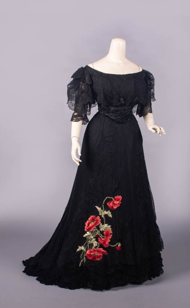 POPPY EMBROIDERED CHANTILLY LACE EVENING GOWN, PITTSBURG, 1905: 2-pc black Chantilly lace evening gown w/ mono bosom, wide bateau neckline, black silk panne velvet shaped cummerbund waistband, trained skirt embroidered w/ poppy motif in shaded floss silk, hem w/ n