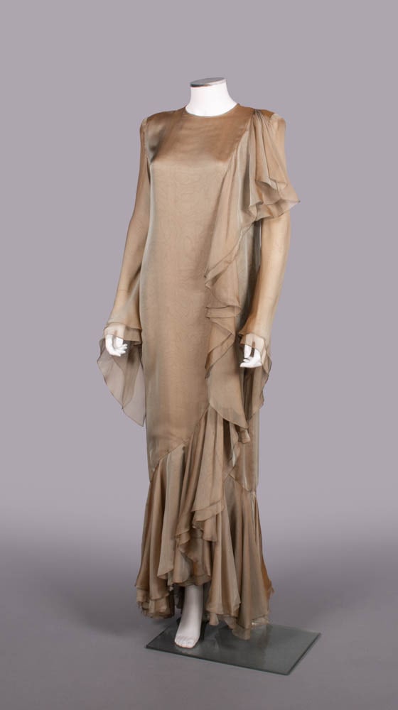 BILL BLASS RUNWAY SHOT SILK CHIFFON GOWN, USA, A/W 1993: Multilayer bronze to sage shot silk chiffon evening gown w/ round neck opening, long sleeve w/ shaped hanging cuff, double panel from left SH continuing into hem flounce, label “Bill Blass”, B