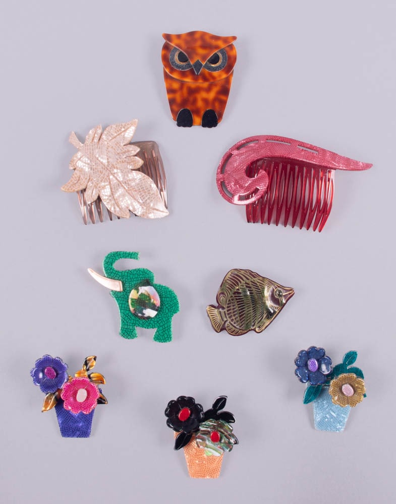 SIX LEA STEIN BROOCHES & TWO UNSIGNED HAIR COMBS, PARIS: 3 Potted Flower brooches, all stamped “Lea Stein, Paris”: 1 in orange pot, 1 in blue pot & 1 in purple pot 1.5” x 2”, (minor residue & light scratching); 1 green elephant brooch, s