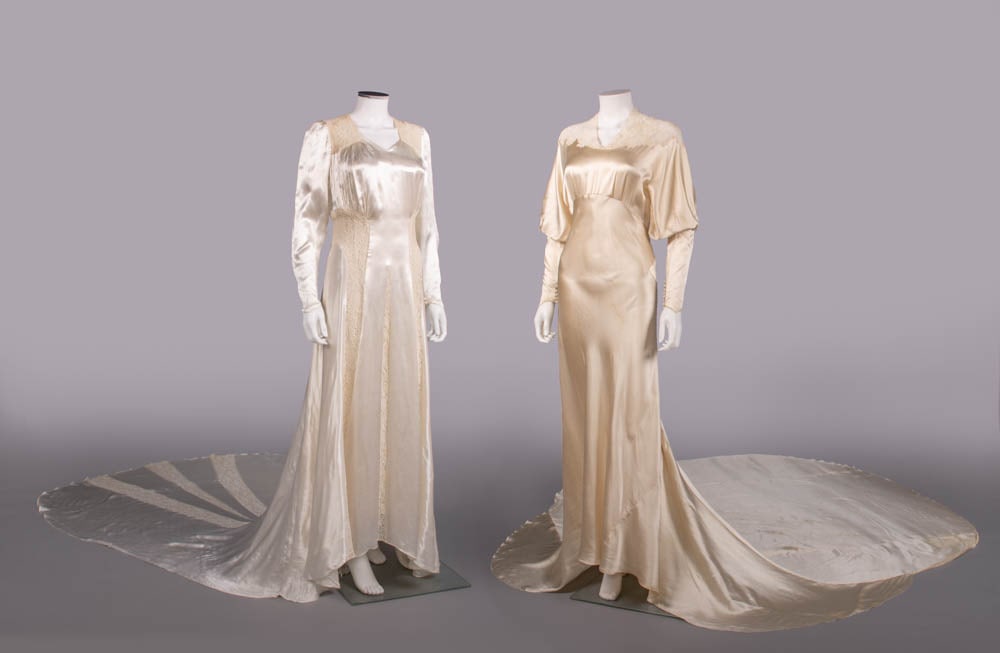 TWO SILK SATIN WEDDING GOWNS, 1934-1938: 1 cream silk satin w/ mm lace yoke, full dolman sleeve into fitted gauntlet w/ self-covered button closures, circular cathedral length train, c. 1934, B 36”, W 27”, L 58”-140”,