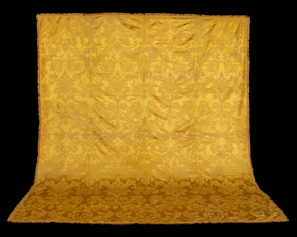SILK DAMASK COVERLET, ITALY, LATE 17TH C: Coverlet of yellow silk damask in symmetrical ogival pattern of latticed leaves, blossoms & palmettes, yellow silk woven band & knotted tassel fringe at perimeter, several pieces seamed selvedge-selve