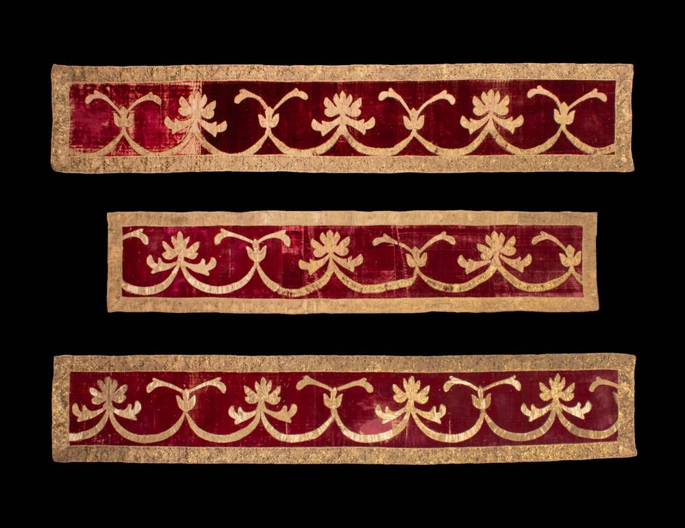 THREE GILT & SILK VELVET VALANCES, SPAIN, c. 1700: 3 red silk velvet valances w/ stylized lotus flower motifs in gilt & cotton applique over paper, gold & cotton galloon border, one 13” x 61.75”, (tiny-0.25” holes); one 13.75” 