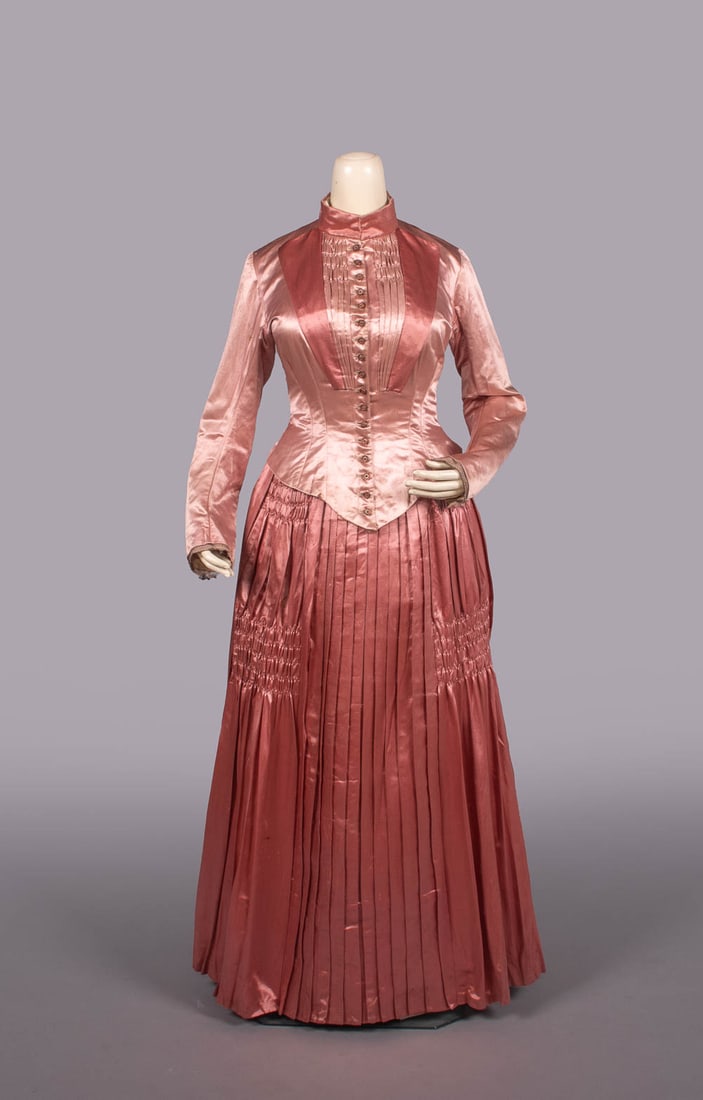 PINK SILK SATIN AFTERNOON OR DINNER DRESS, c. 1880: 2-pc two tone pink silk satin gown w/ metallic shanked CF button closures, knitted metallic gauze cuff overlay, elaborate ruching & pleating to skirt, white cotton lining w/ metallic stripe, bodice B