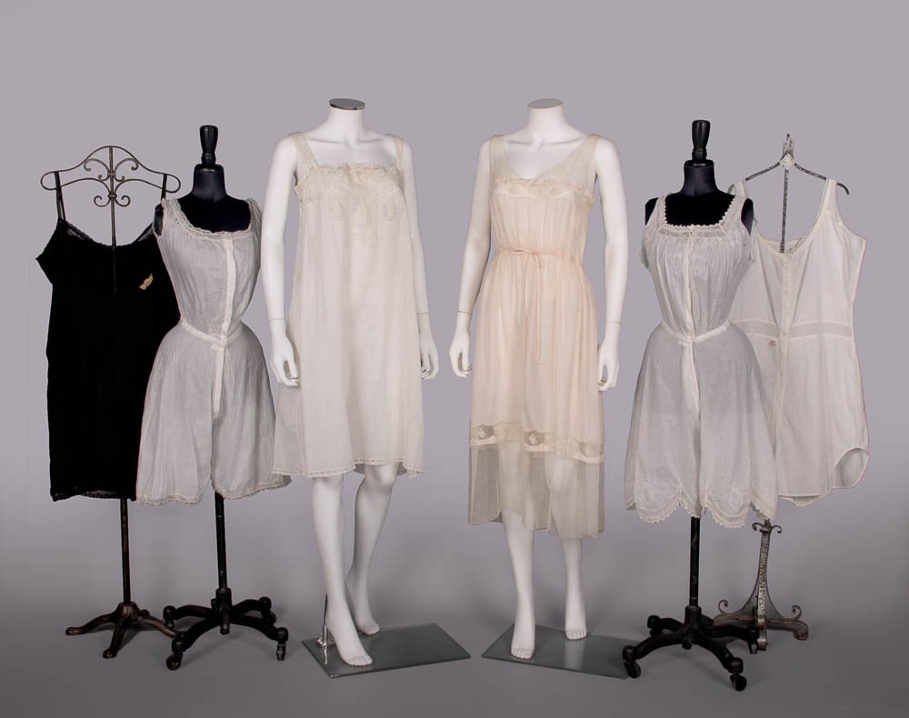 FIVE SILK OR COTTON SLIPS & CAMIKNICKERS, 1910-1920s: 1 black silk chemise w/lace & ribbon, B 46", L 38", (straps fraying, repairs/few holes to 1”, openings to 3”, lace removed SSs) good; 1 white cotton camiknickers w/Madeira embroidery, B 34