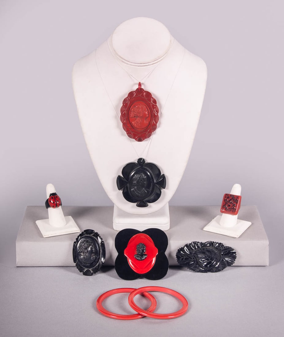 RED & BLACK BAKELITE OR COMPOSITION JEWELRY, 1930-1940s: 1 ladybug ring, sz 7.5, 0.5" x 1"; 1 black cameo brooch, 1.75" x 2.5", (moderate residue, cameo off-center); 1 red cameo pendant, 2" x 2.75", (string N/I, minor residue); 1 black cameo pendant, 2.5" x