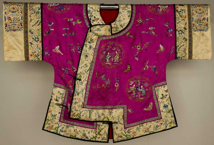 FUSCHIA SILK JACKET, CHINA, EARLY 20TH C: Damask embroidered w/ figural rondels, butterflies & flowers, the white borders & sleeve bands w/ colorful embroidery, L 30", (stains on sleeve bands & around outside of collar) very good.