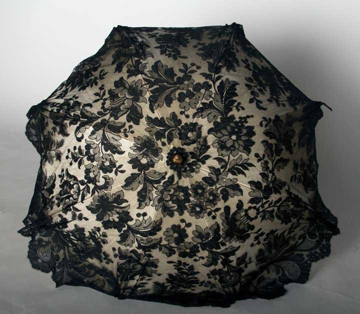 TIFFANY LACE PARASOL, 1900-1910: White satin canopy covered w/ black Spanish lace, wooden stick w/ gold & clear crystal handle, carved horn tip, "Tiffany & Co." etched on inner hinge, L 38", excellent.