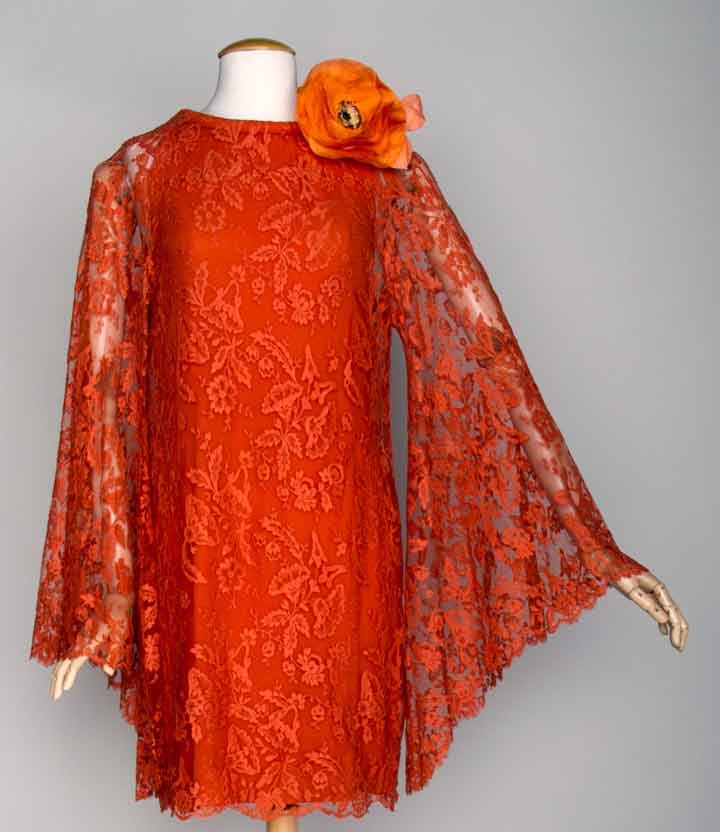 PIERRE CARDIN CORAL LACE MINI DRESS, c. 1970: Coral lace w/ sleeveless silk underdress, rouleau signature collar, angel sleeves, orange silk poppy, label "Pierre Cardin Boutique Paris", B 34", H 40", L 36", (holes in lace at both shoulders) very 