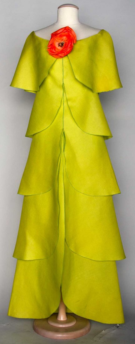 PIERRE CARDIN COUTURE EVENING DRESS, 1970s: Chartreuse silk, 5 overlapping tiers on A-line dress, CF orange silk poppy, label "Pierre Cardin Paris", B 34", H 38", L 55", (yellow fading on all tiers) fair. Provenance: Mme. Erna de Paz, Argentine