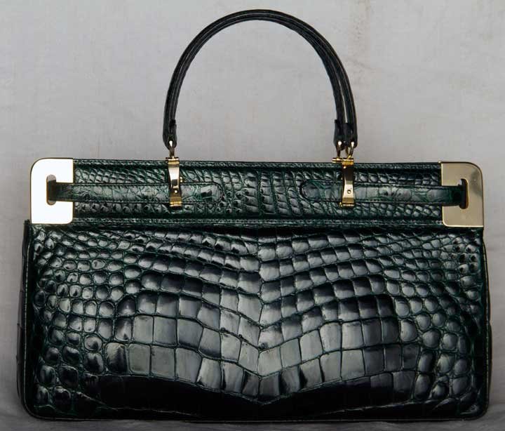 GREEN CROCODILE HANDBAG, ITALY, MID 20TH C: Dark forest green, double handle, side straps snap into brass hardware to secure closure, similar design as Hermes Kelly bag, 2 large interior pockets w/ zipper pocket on each side, label "Righini Pia