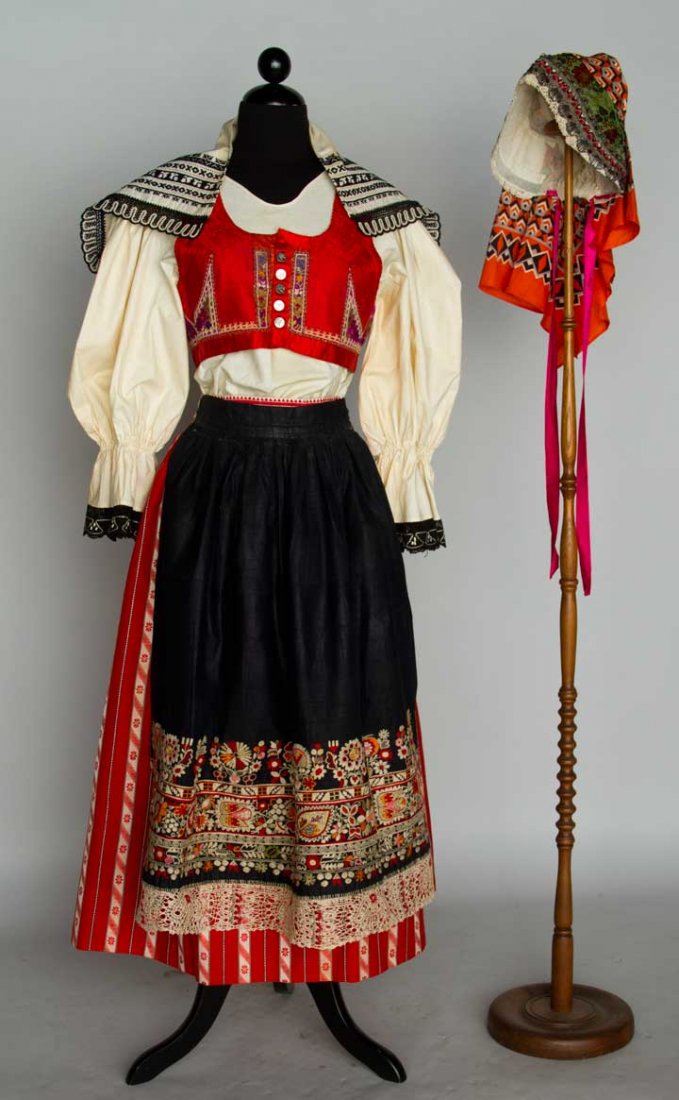 WOMAN'S FOLK COSTUME, CZECHOSLOVAKIA, c. 1930: 6 pieces: 1 muslin blouse w/ black lace, 1 wool skirt w/ red & white stripes, 1 apron colorfully embroidered on indigo cotton, 1 vest of magenta brocade w/ red trim, 1 bonnet of brocade & metallic lac