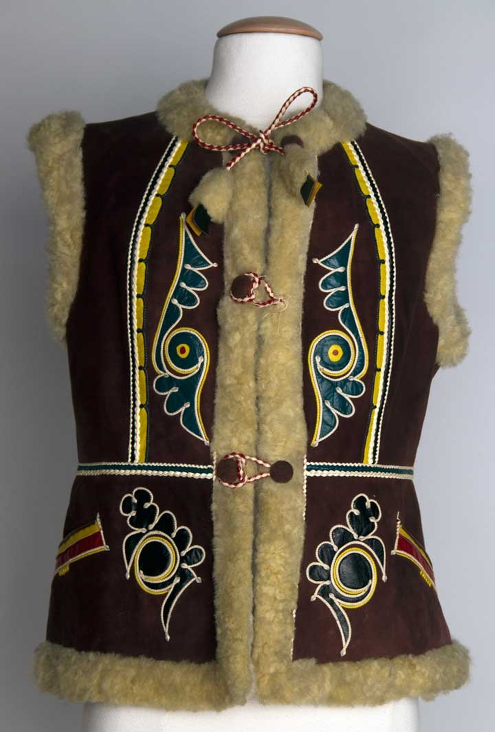 MAN'S FOLK VEST, YUGOSLAVIA, 1938: Brown suede w/ cream shearling lining, leather appliques in green, yellow, & red, Ch 34", L 23.5", excellent.