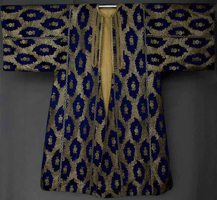 GOLD BROCADE CAFTAN, MIDDLE EAST, 20TH C: Sapphire blue w/ metallic gold brocade, gold braid trim & gold & blue trim, gold buttons, Slv-Slv 58.5", L 53", (purple silk damask lining replaced w/ yellow rayon) excellent.