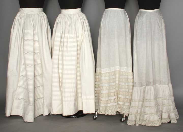 FOUR COTTON PETTICOATS, 19TH C: 2 c. 1860: cartridge pleated into waistbands, horizontally tucked CF panel, 1 w/ eyelet embroidery & 1 w/ scalloped hem; 2 c. 1900: deep flounced hems w/ Valenciennes lace insertions; (few small holes