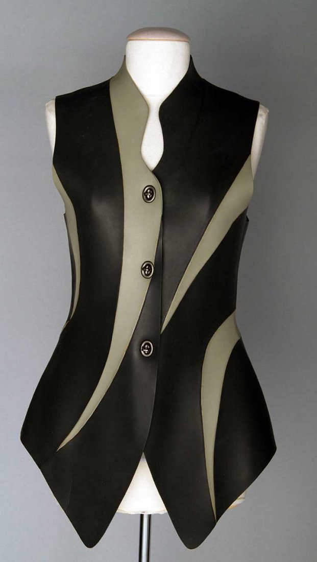 JUNKO KOSHINO RUBBER VEST, JAPAN, 20TH C: Charcoal rubber pieced w/ light gray shapes, asymmetrical neckline, longer in front, back fitted, 3 metal toggles, labeled "Tokyo Junko Koshino, Made in Japan", B 33", W 29", Front L 31", Back L 24",