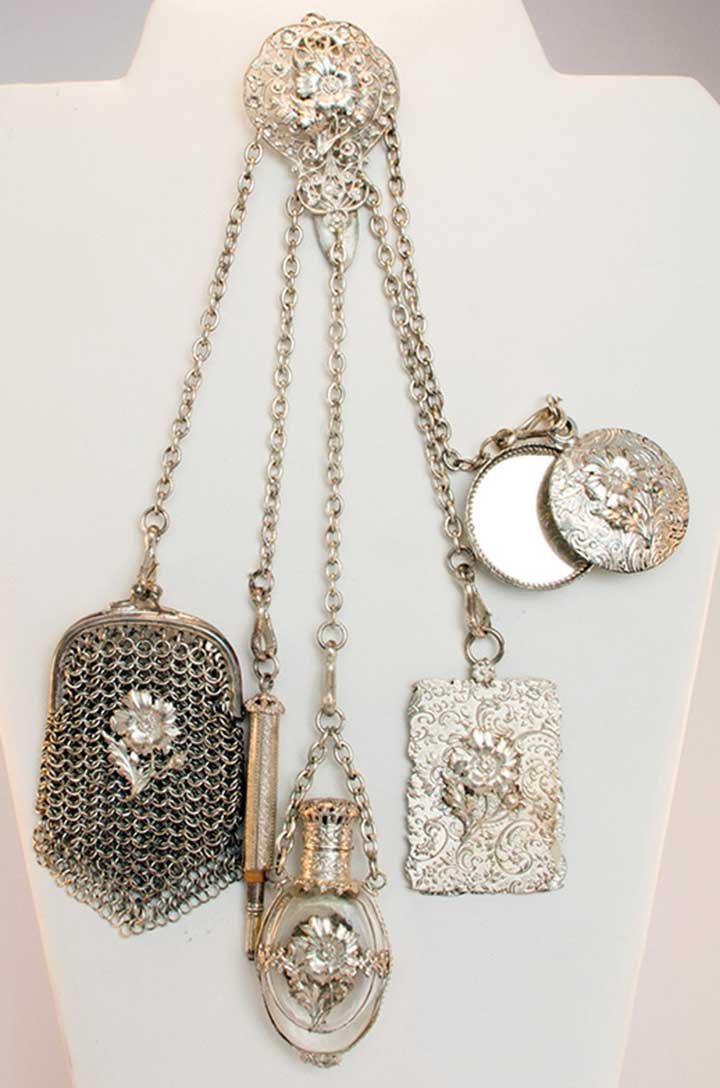TWO SILVER CHATELAINES, 1850-1890: 1 silver pot metal floral open-work clasp w/ 5 chains holding small mesh purse, pencil, perfume vial, notecard & mirror, excellent; 1 cut steel clasp w/ 6 long steel chains holding various shaped keys