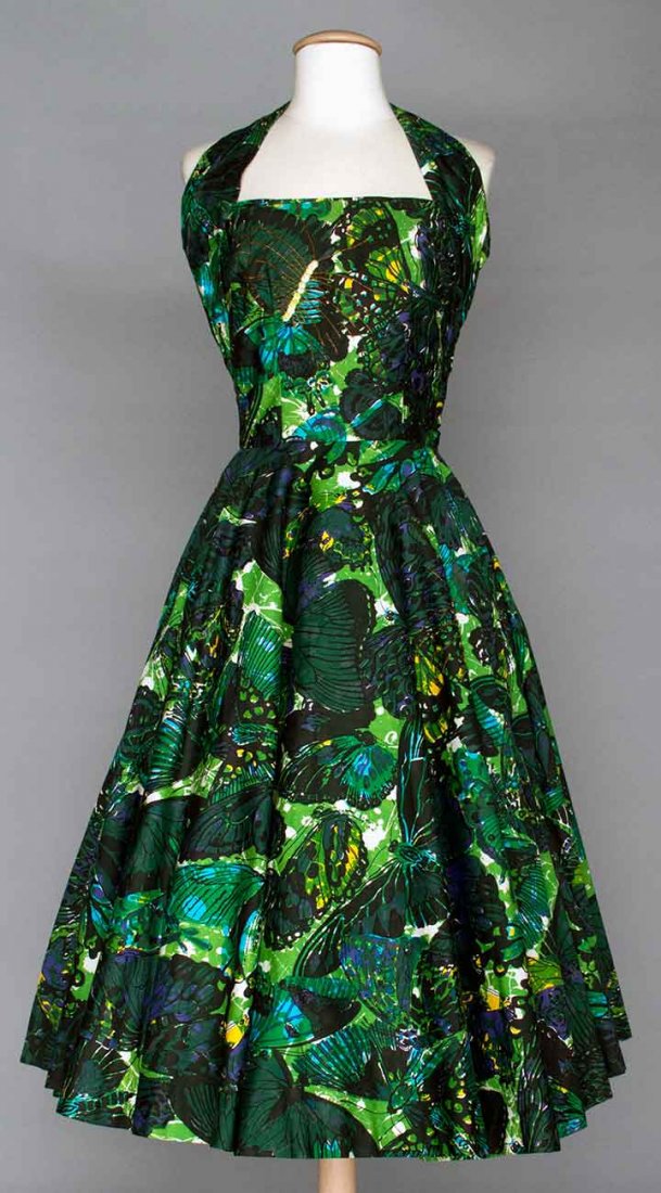 PRINTED PARTY DRESS, MID 1950s: Cotton butterfly print in shades of green & blue, 1 beaded & sequined butterfly on skirt & on bodice, fitted bodice w/ halter neck, full circle skirt w/ attached crinoline petticoat, B 33", W 25", L 4
