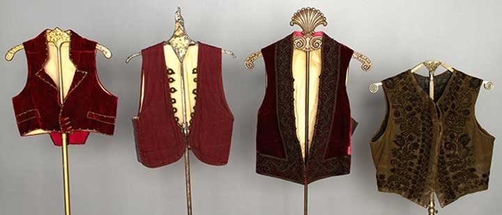 FOUR MEN'S REGIONAL VESTS, MID-LATE 19TH C: 1 Slovakian brown leather w/ black embroidery; 1 Albanian red & blue cotton pinstripe; 2 Spanish red velvet: 1 w/ black soutache & 1 w/ gold soutache; very good-excellent.